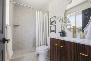 Bathroom featuring a fluted wood vanity with gold-tone hardware, a circular mirror, and a gold-tone faucet