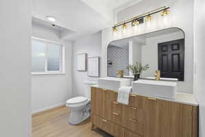 Bathroom featuring a dual vanity with rectangular vessel sinks, gold-finish faucets, and a light wood-finish cabinet with textured fronts