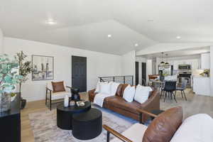 Spacious open-concept living area featuring vaulted ceilings, light wood-finish flooring, and recessed lighting