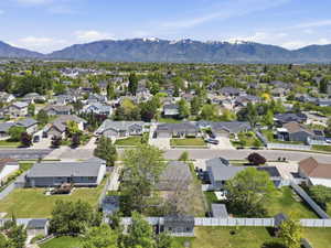 Expansive residential neighborhood with varied architectural styles, mature trees, paved streets, and a mountainous backdrop