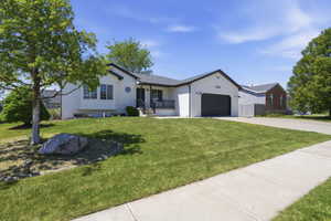 Modern ranch-style home featuring a white exterior, dark trim, and a black garage door