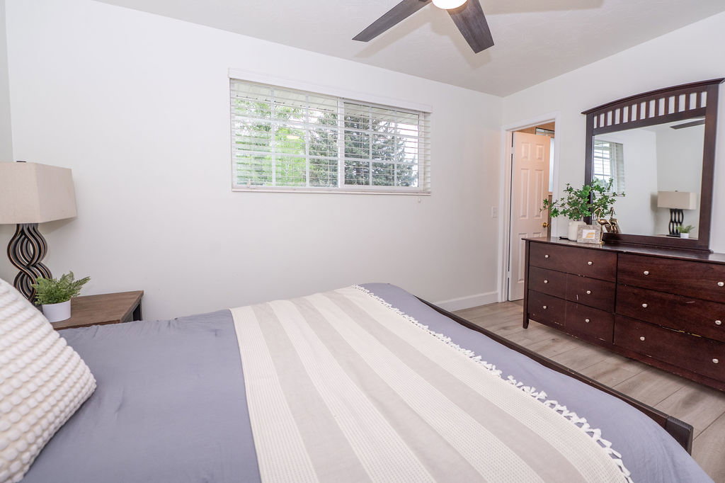 Bedroom featuring a window with horizontal blinds, wood-finish flooring, and a ceiling fan with light fixture