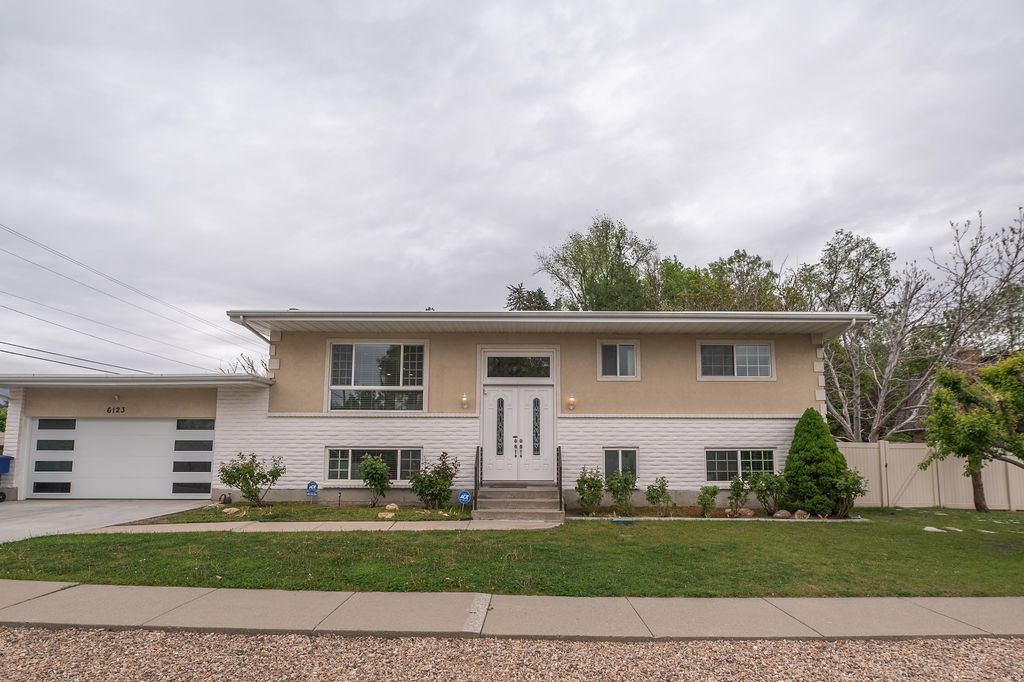 Featuring a modern garage door, a prominent front entry with double doors, and a combination of stucco and horizontal siding