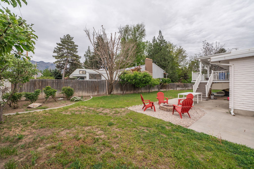 Spacious backyard with a gravel fire pit area, concrete patio, and mature trees