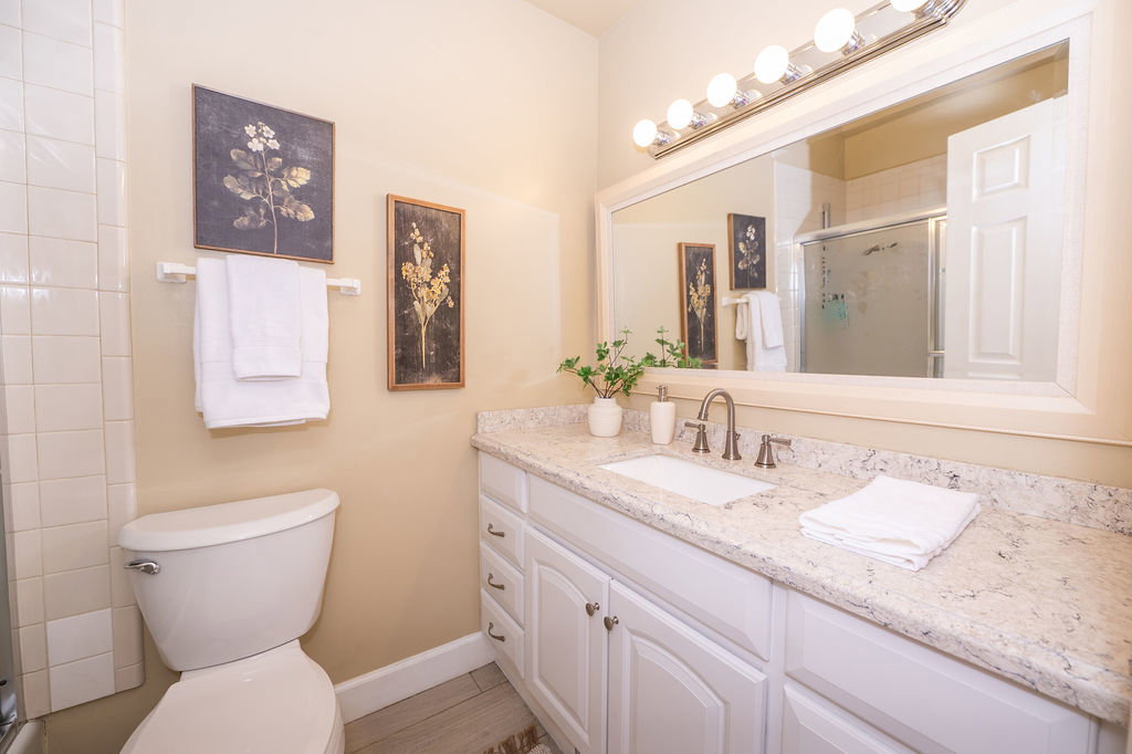 Bathroom featuring a white vanity with an integrated sink, a speckled countertop, and a bronze-finish faucet