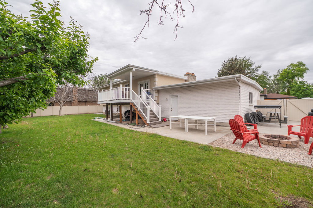 Expansive backyard featuring a lush lawn, concrete patio, and a dedicated gravel area with a built-in fire pit