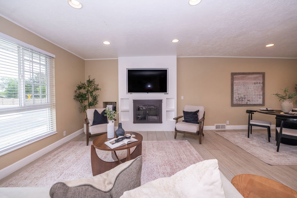 Living area featuring wood-finish flooring, recessed lighting, a white fireplace surround with integrated shelving, and window blinds