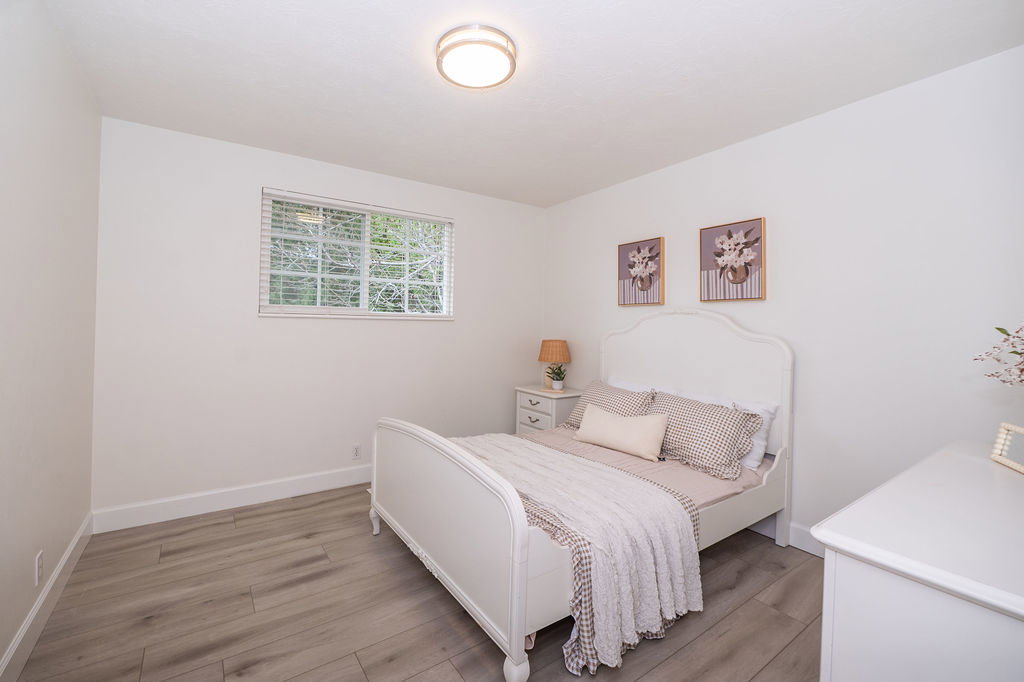 Bright room featuring light wood-finish flooring, white baseboards, and a single window with blinds