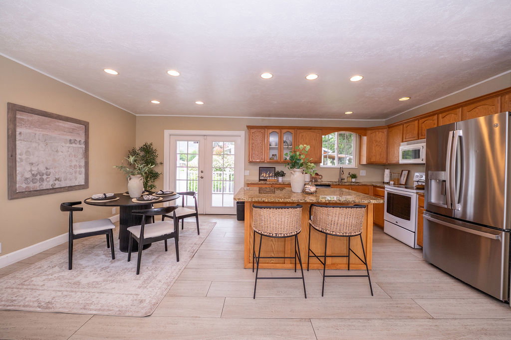 Spacious kitchen and dining area with light wood cabinetry, a granite-top island, and stainless steel appliances