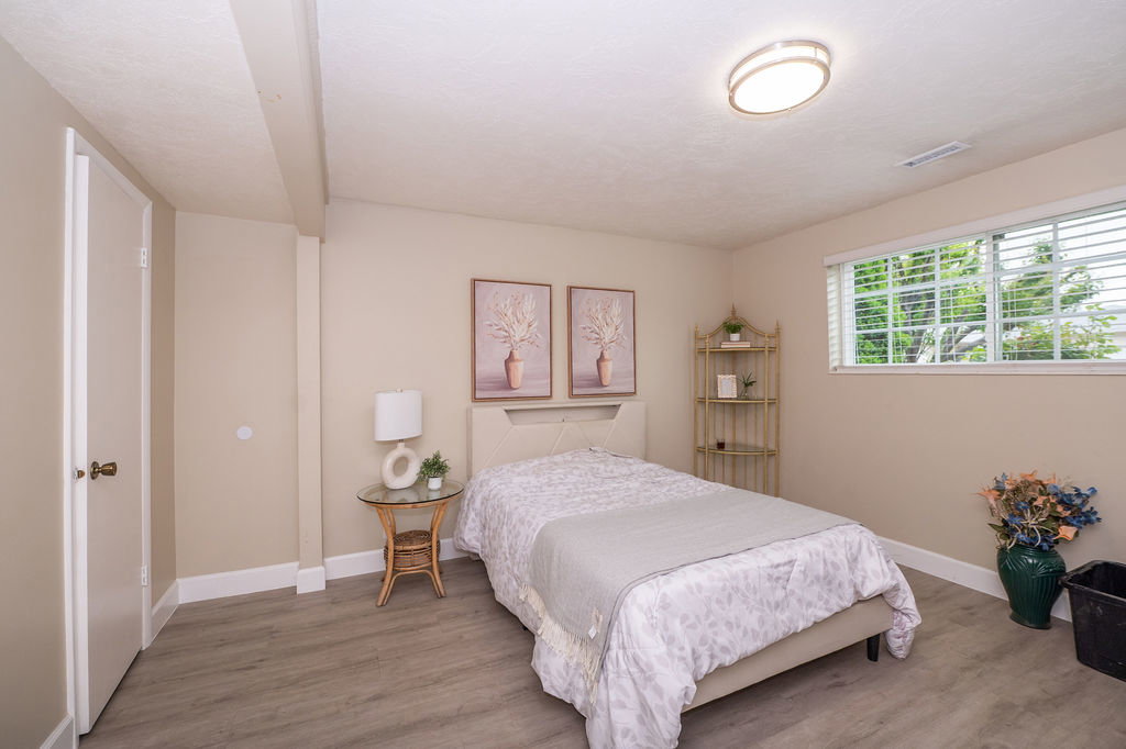 Bedroom featuring wood-finish flooring, a double window with blinds, and light-toned walls