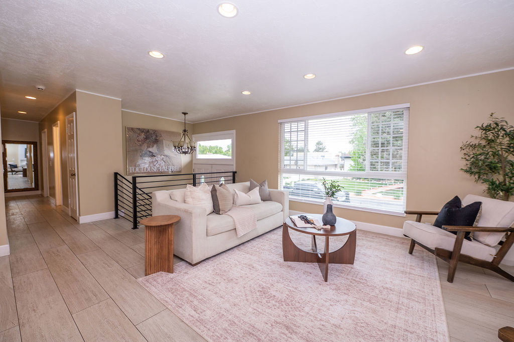 Spacious living area featuring plank-style tile flooring, recessed lighting, and a large picture window with horizontal blinds