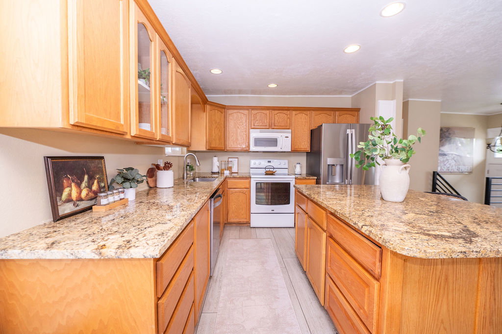 Kitchen featuring wood-finish cabinetry, granite countertops, stainless steel appliances, a kitchen island, and recessed lighting