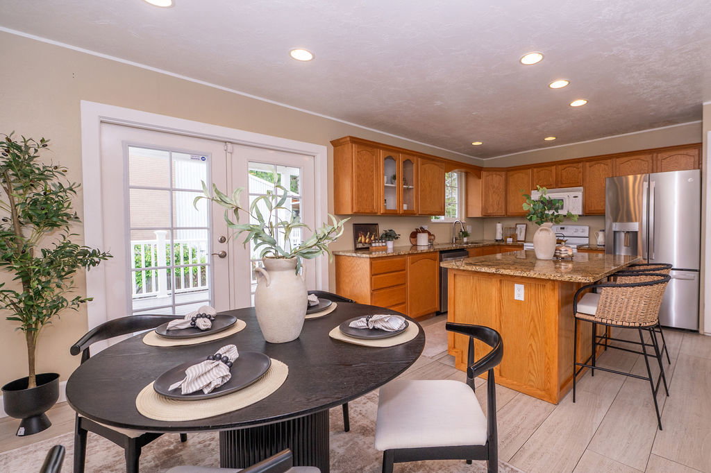 Kitchen and dining area featuring a central island with a stone-finish countertop, wood-finish cabinetry, stainless steel appliances, recessed lighting, and light wood-finish flooring