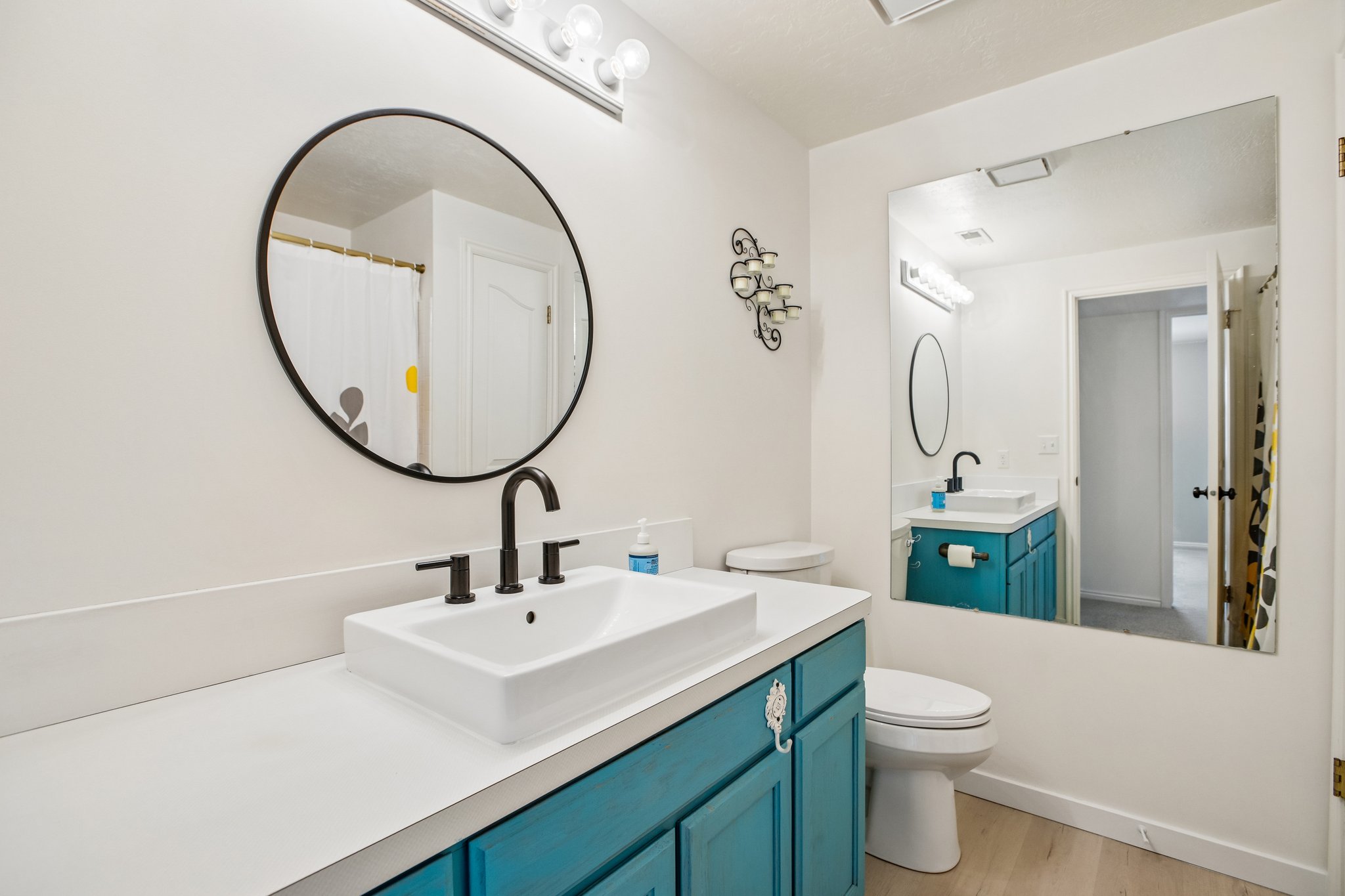 Vanity featuring a rectangular vessel sink with matte black faucet, a round black-framed mirror, and a light-colored countertop