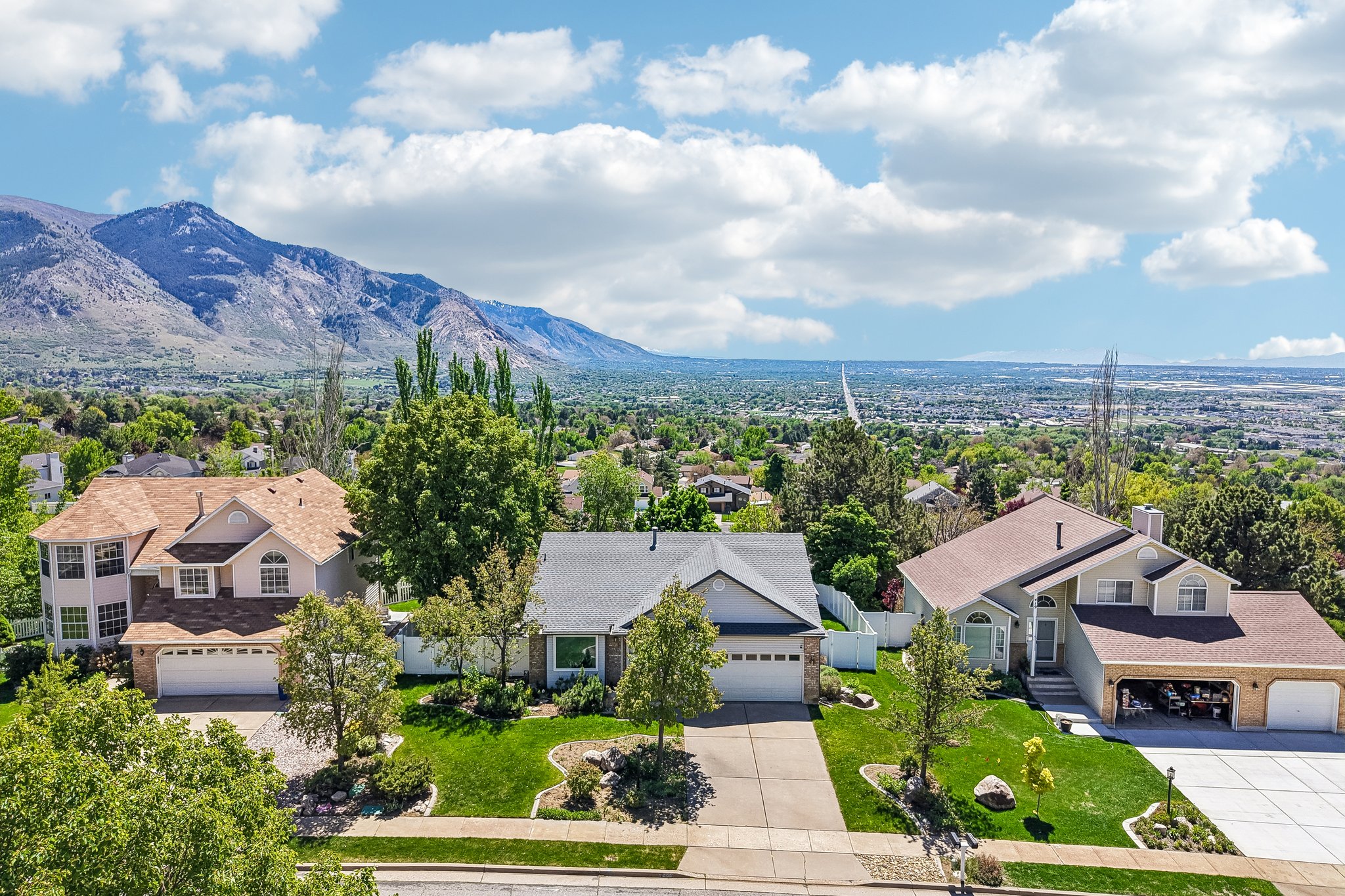 Traditional residence featuring a two-car garage, established front yard landscaping, and a paved driveway