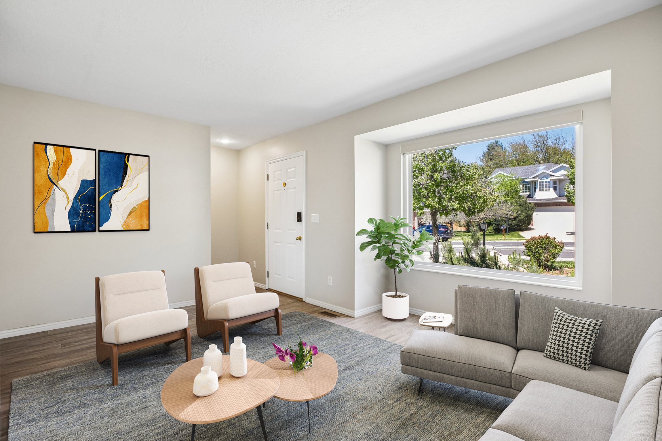 Bright living area featuring wood-finish flooring, light neutral wall tones, and a large picture window