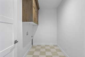 Utility room with checkerboard tile flooring, white walls, and built-in wood-finish cabinetry