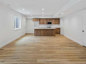 Spacious open-concept room featuring wood-finish flooring, recessed lighting, and a modern kitchen area
