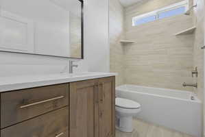 Bathroom featuring a wood-finish vanity with a light-toned countertop, a rectangular undermount sink, and a brushed nickel faucet