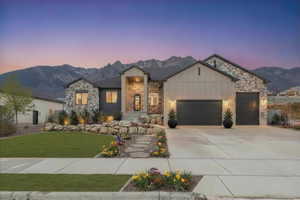 Contemporary residence featuring a stone and board-and-batten facade, integrated two-car garage, and a prominent covered entryway