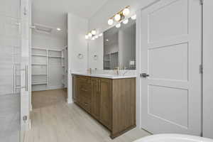 Bathroom featuring a double vanity with wood-finish cabinetry, white countertops, dual undermount sinks, and gold-finish fixtures