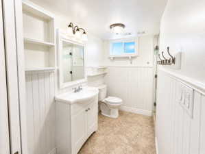 Bathroom with vanity, wainscoting, and light tile patterned flooring