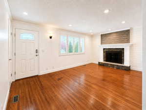 Unfurnished living room featuring hardwood / wood-style flooring, a fireplace, recessed lighting