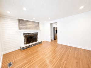 Unfurnished living room with light wood-style flooring, a stone fireplace, recessed lighting