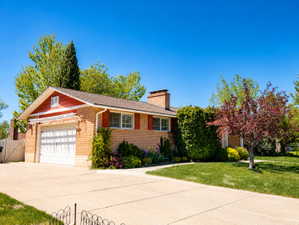 Ranch-style house with brick siding, a gate, a chimney, driveway, and a front lawn