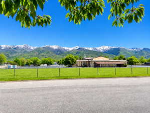 Expansive green space with distant mountain backdrop featuring snow-capped peaks