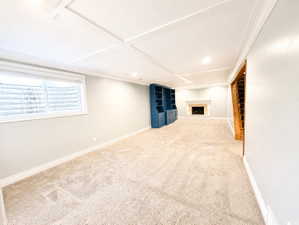 Below grade area with light colored carpet, a fireplace and built in entertainment cabinetry