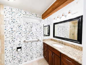 Bathroom featuring vanity, tiled shower, and beam ceiling