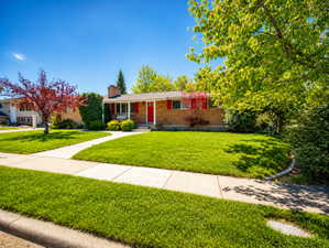 Ranch-style house with brick siding, a front lawn, and a chimney
