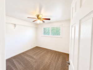 Spare room with ceiling fan, dark colored carpet, and ornamental molding