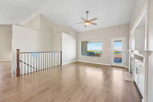 Unfurnished living room featuring light wood-style floors, ceiling fan, and vaulted ceiling