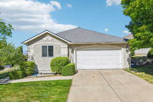 Ranch-style home featuring a garage, driveway, stucco siding, and roof with shingles