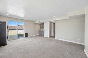 Unfurnished living room with light colored carpet, a textured ceiling, and recessed lighting