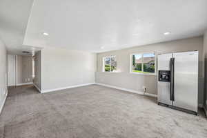 Unfurnished living room with light carpet, a textured ceiling, and recessed lighting