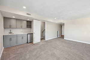 Kitchen with gray cabinetry, light countertops, light colored carpet, a textured ceiling, and open shelves