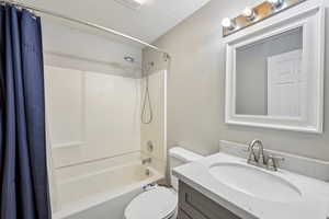 Bathroom featuring vanity, shower / bathtub combination with curtain, and a textured ceiling