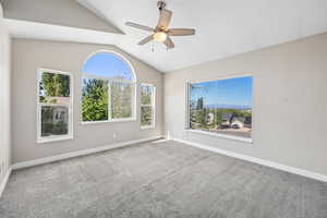 Carpeted empty room featuring lofted ceiling and ceiling fan