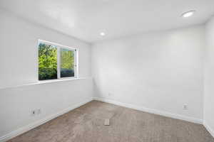 Carpeted spare room featuring baseboards and recessed lighting