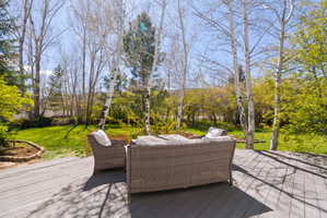 Spacious outdoor deck with composite decking, surrounded by mature trees and a vibrant lawn