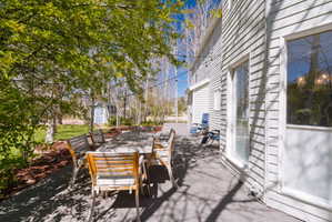 Expansive outdoor patio featuring a gray deck surface, string lighting, and mature trees providing natural shade