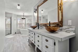 Double vanity featuring vessel sinks, a large ornate mirror, and mosaic tile backsplash