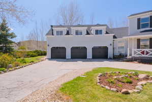 Light-toned siding exterior featuring a three-car garage with dark paneled doors