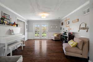 French doors opening to exterior, wood-finish flooring, wainscoting, crown molding, and recessed lighting