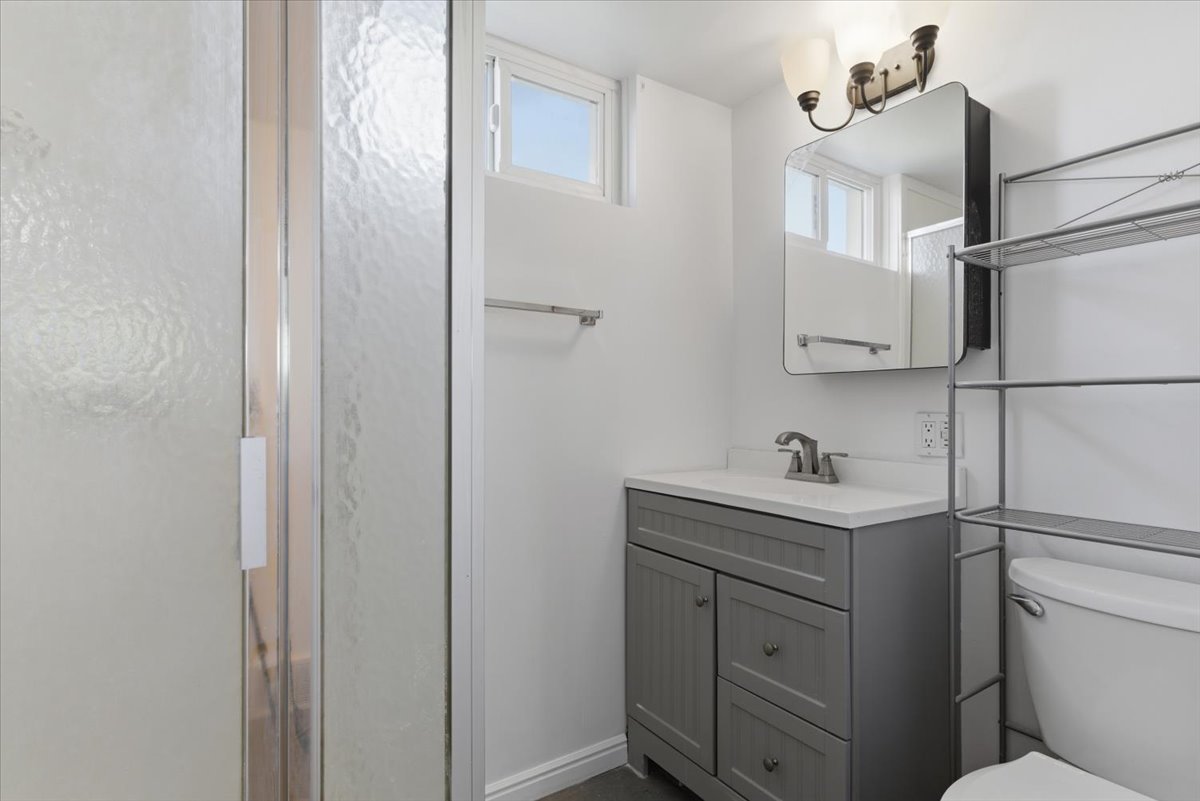 Bathroom featuring a gray vanity with white countertop, chrome faucet, and a wall-mounted medicine cabinet