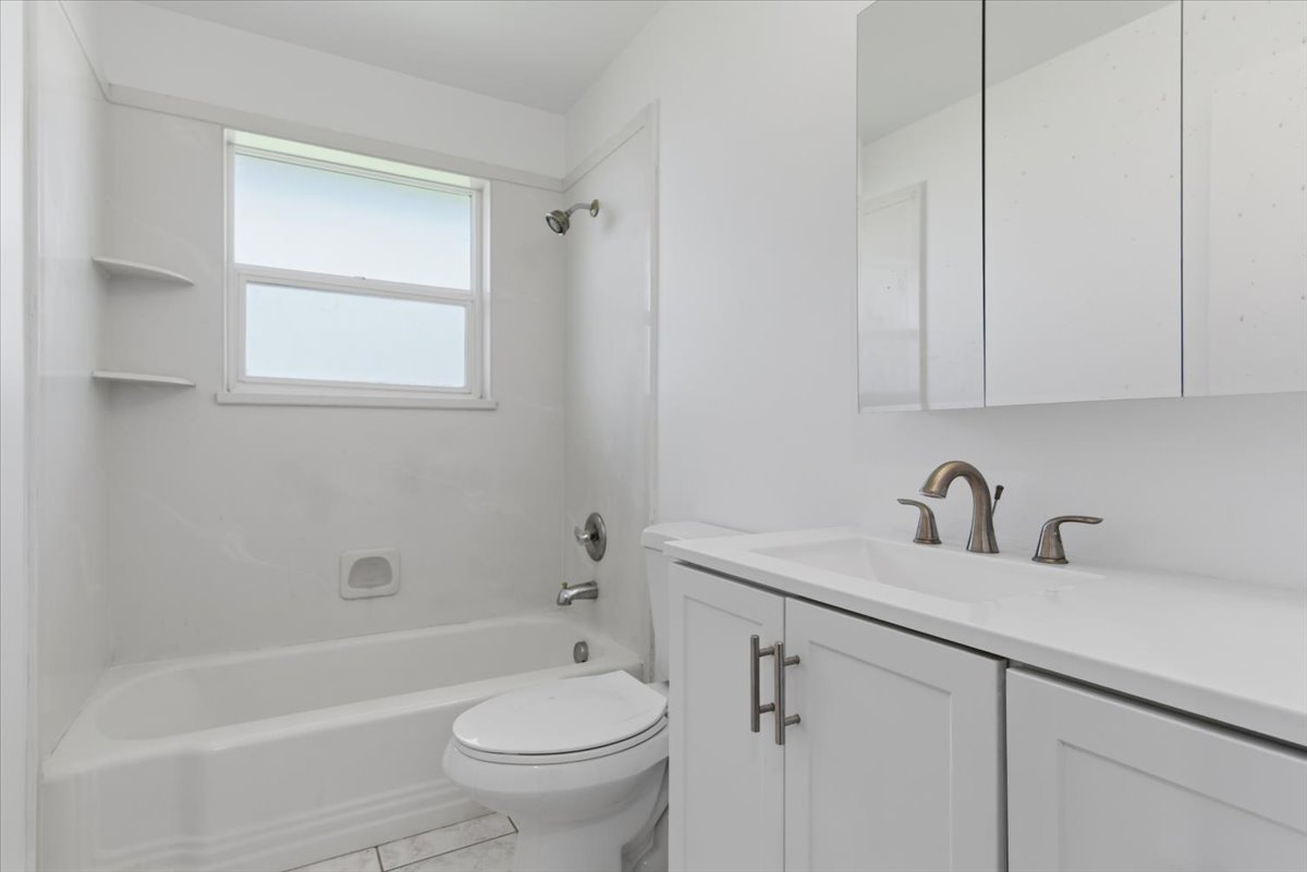 Bathroom featuring a white vanity with integrated sink, brushed nickel faucet, and a large mirrored medicine cabinet