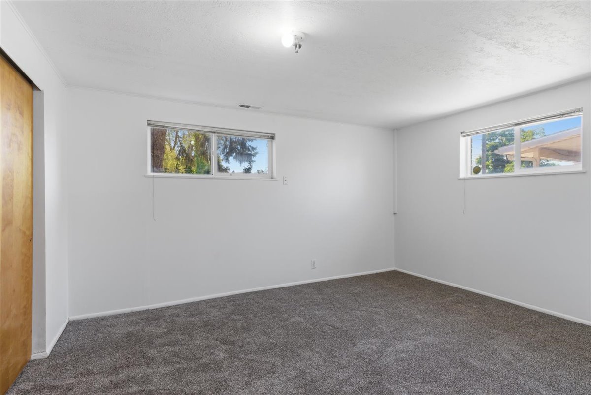 Spacious room featuring gray carpet flooring, white painted walls, and two horizontal windows